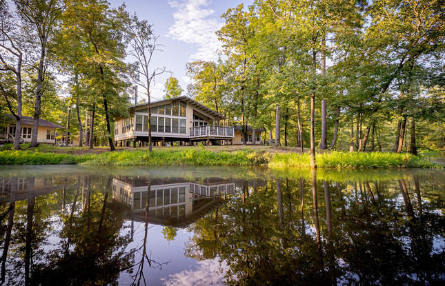 Chemin-A-Haut State Park cabins reflected in the water of the bayou and surrounded by bright green trees.