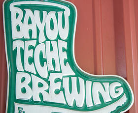Green metal sign saying Bayou Teche Brewing