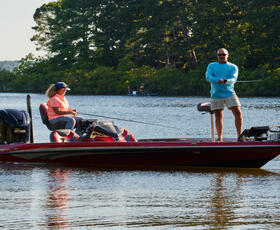 Man and woman on a red boat fishing from lake waters of Toledo Bend Reservoir at South Toledo Bend State Park in Louisiana.
