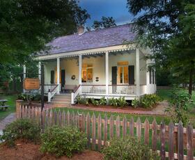 The exterior of the cozy Jean Baptiste Lang House, with warm light shining through the windows. Credit: Louisiana Northshore