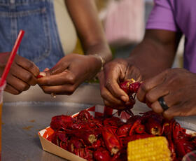 Two people peel crawfish together.