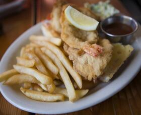 An open-faced fried shrimp sandwich next to golden french fries at Herby K’s restaurant.