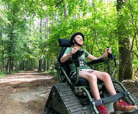 Person using an all-terrain wheelchair on a forest trail at Lake D’Arbonne State Park.