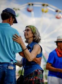 Two people dance at the Breaux Bridge Crawfish festival. A ferris wheel is behind them.